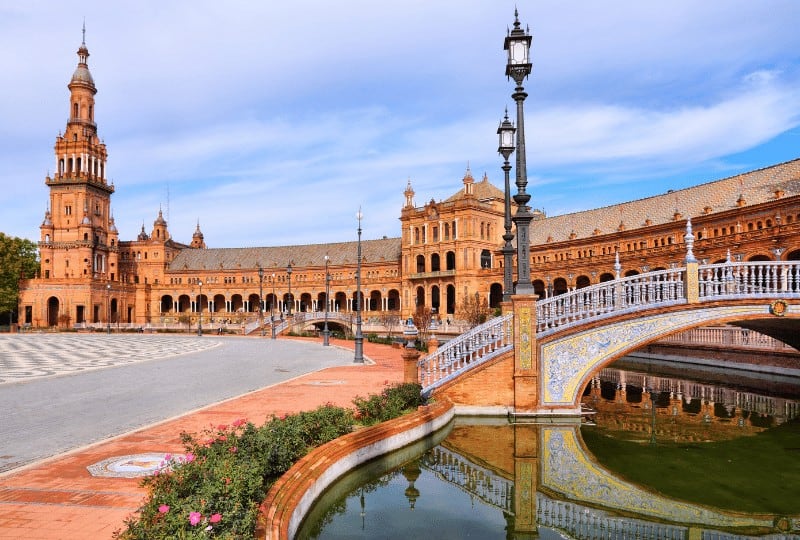 side view  of the river and bridge in the plaza de espana on a cloudy day in seville
