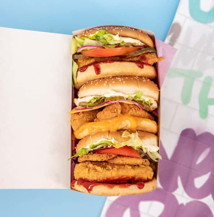a long rectangle box filled with three vegan burgers on a colorful background in warsaw