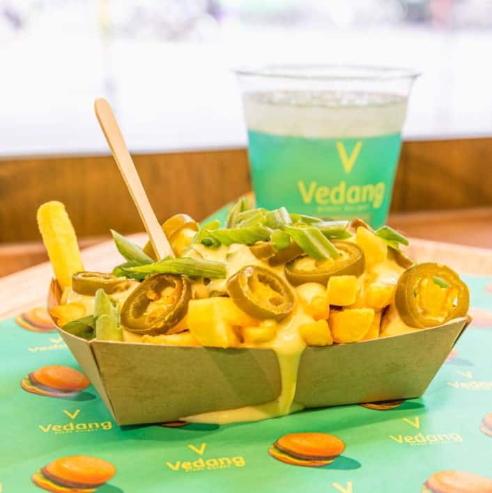 an order of vegan cheese covered french fries in a small paper boat covered in jalapeno slices at vedang in koln germant