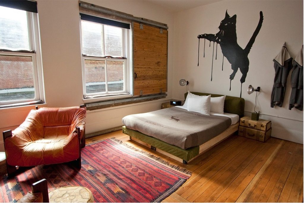 modern guest room with a fiant jumping cat mural above the double bed with large bright windows at ace hotels portland