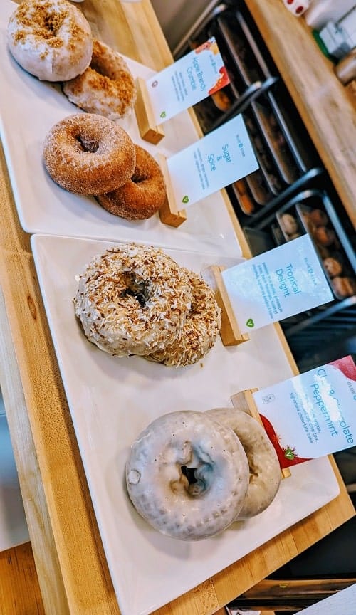 four vegan cake donuts on a white tray inside of a dessert case at blue star donuts in portland