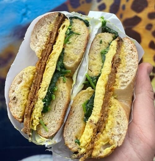 a vegan egg and bacon bagel sandwich cut in half from chubby bunny in portland