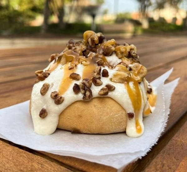 one large vegan cinnamon roll topped with thick cream cheese frosting and candied nuts at cinnaholic in LA