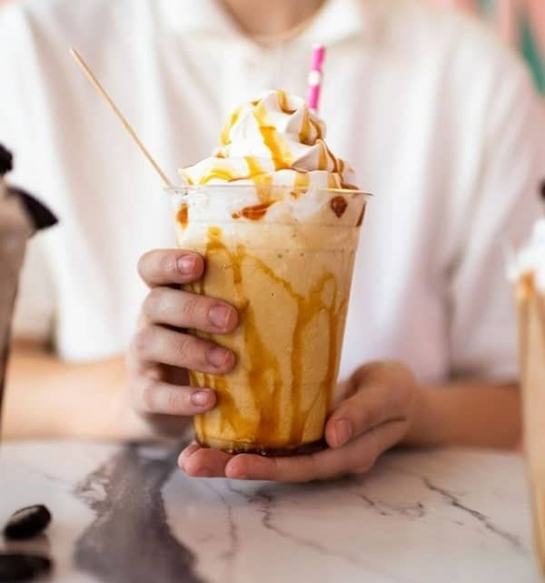 vegan milkshake in a large glass topped with whipped cream and caramel at dear bella in LA