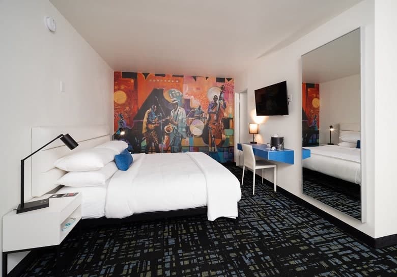 modern guestroom at jupiter hotel with a colorful wall mural and the remaining walls white with dark flooring in portland