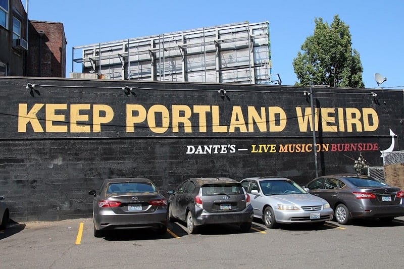 black mural with yellow letters that say keep portland weird on the side of a building