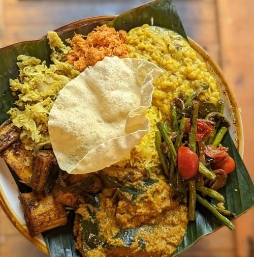 a large platter filled with vegan pumpkin curry, yellow rice, cauliflower mallum, long green beans at mirisata in portland