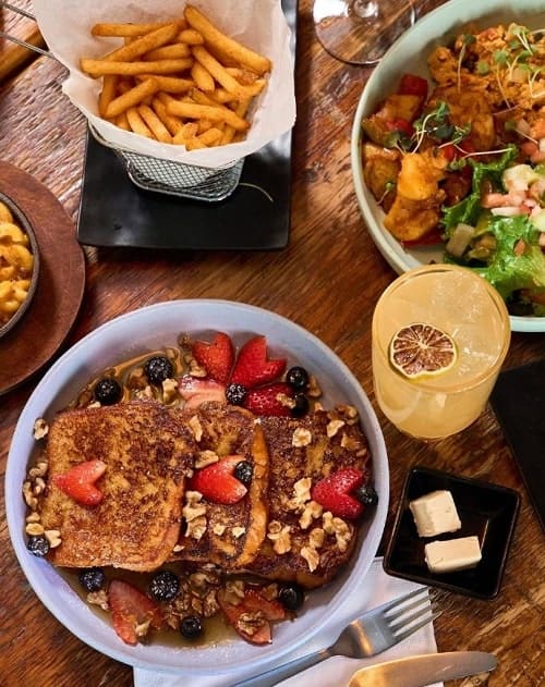 vegan brunch spread with a plate of thick cut french toast, french fries, boozy drinks, and salad at ras plant based in brooklyn