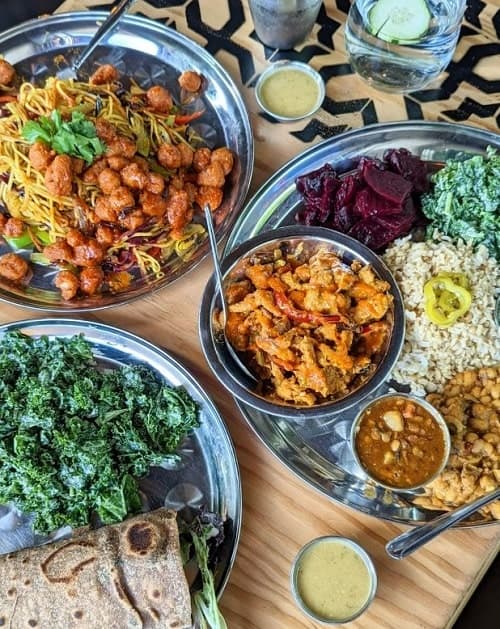 multiple platters of colorful vegan indian dishes from the sudra in portland