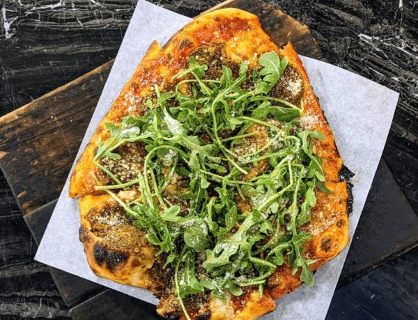 round vegan pizza topped with arugula on a white paper on a black table at virtuous pie in portland