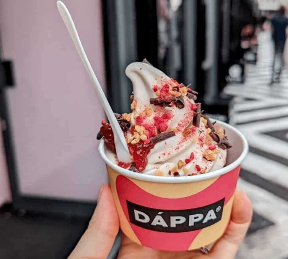 cup of vegan soft serve topped with dried raspberry dust and chocolate chips in london