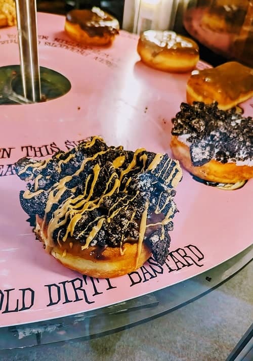 vegan raised donut topped with cookie crumble and a peanut butter drizzle on a pink tray in portland