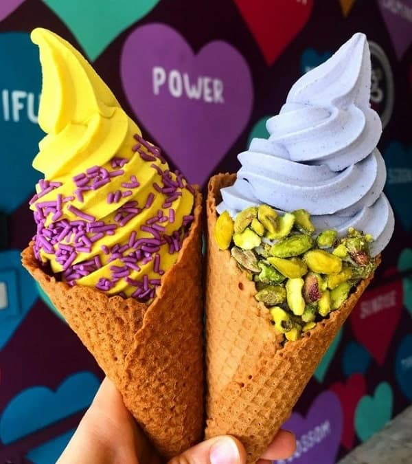 two vegan waffle cones filled with vanilla softserve and lemon and topped with pistachios and purple sprinkles at yoga-urt in LA