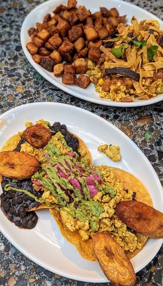 two white oval plates next to each other with vegan plantain brekfast tostadas and a vegan scramble with golden potatoes at cafe flora in seattle