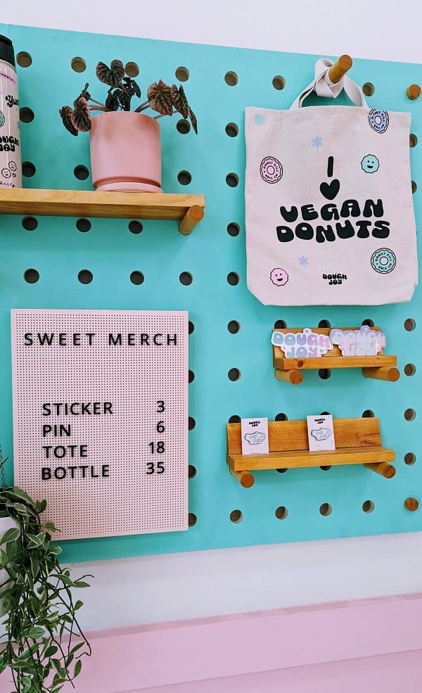 vegan donut merchandise on a turquoise peg board on a pink wall at dough joy in seattle