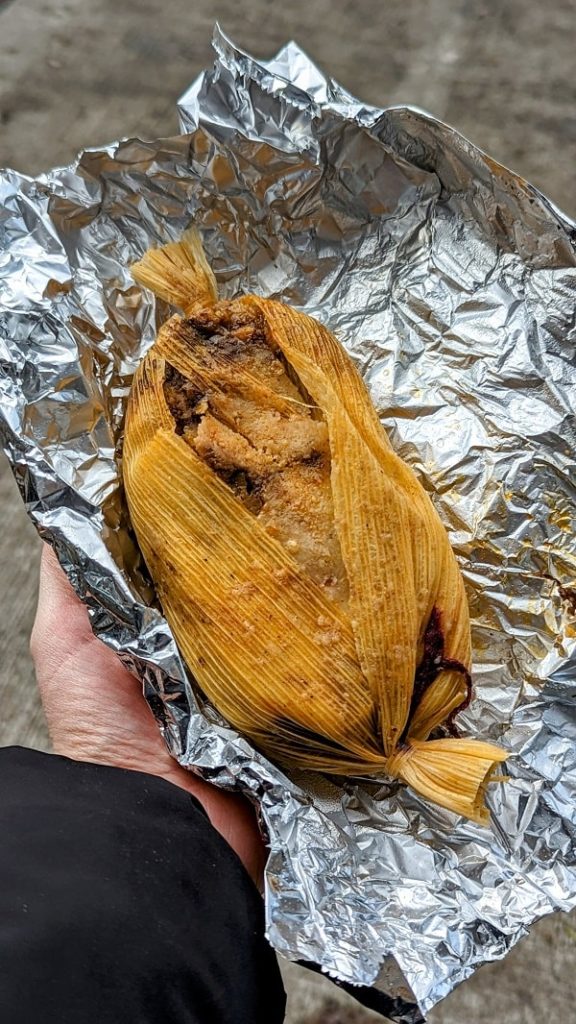 a vegan tamale slightly open from the corn husk on aluminum foil from freelard tamales in seattle