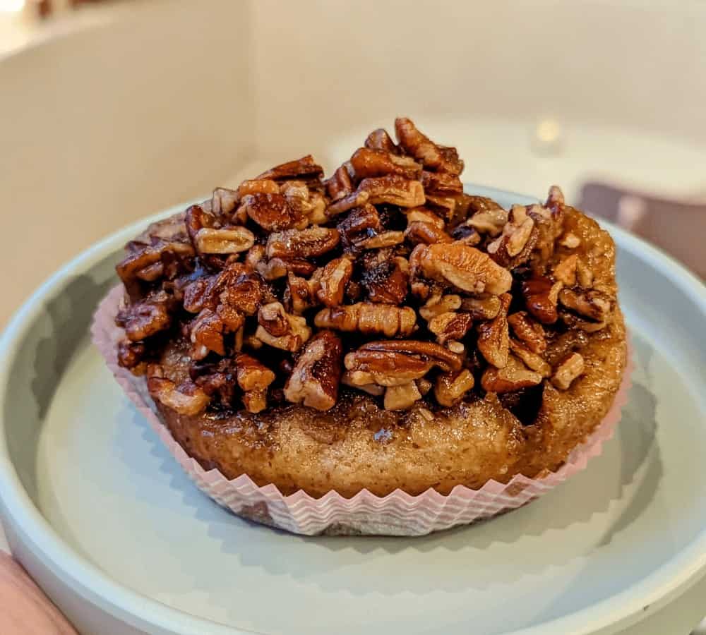 large golden vegan and gluten free pecan sticky bun sitting in the middle of a light blue plate in portland