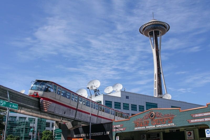 the seattle monorail headed away from the seattle center with the space needle in the background