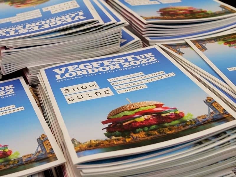 stacks of colorful paper guides to the vegfest uk events 
