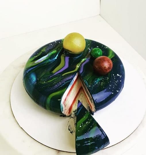 a round vegan cake topped with a colorful mirror glaze that looks like the galaxy from blue neige patisserie in NYC