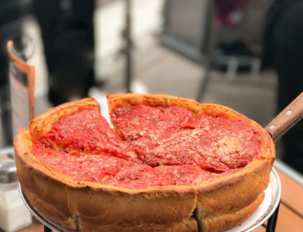large round vegan deep dish chicago style pizza with a thick crust and topped with marinara sitting on a stand in chicago