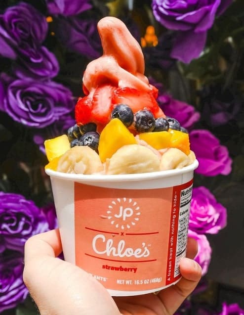 a vegan ice cream sundae in a pink and white bowl topped with sliced strawberries, banana and blueberries from chloes fruit co. in NYC