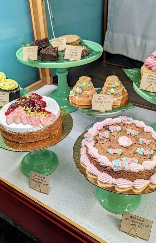 a variety of vegan cakes and desserts on mint green cake stands at the vegan bakery confectionary in nyc