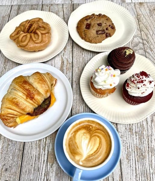 multiple vegan pastries next to a plate of cookies and brownies and a cup of coffee at innocent yesterday in NYC 