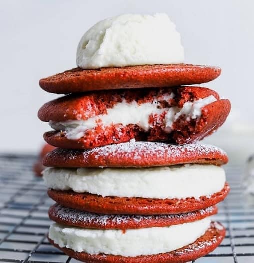 a stack of three bright red vegan whoopie pies filled with buttercream frosting from sensible edibles in NYC