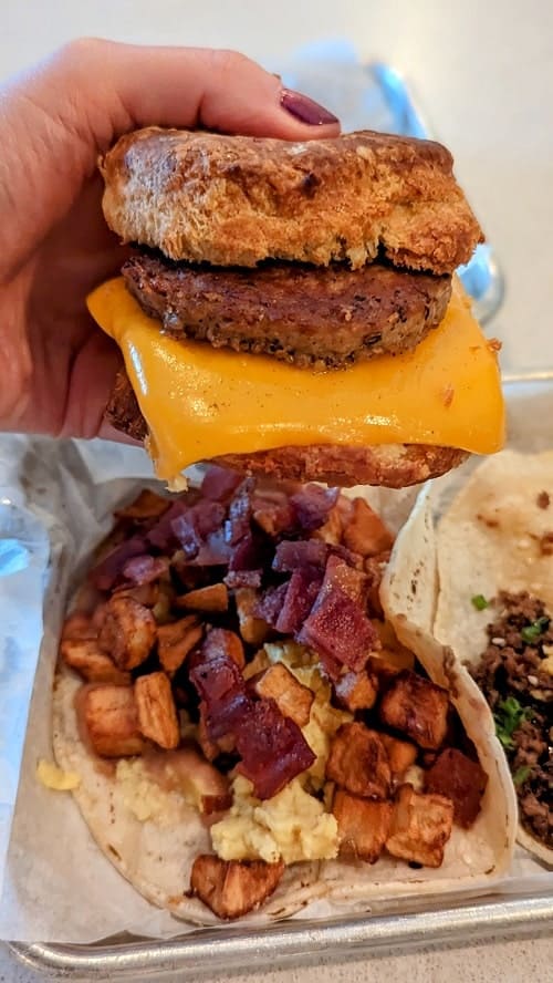 vegan breakfast biscuit sandwich with melted cheese held above at taco at tellus joe in austin