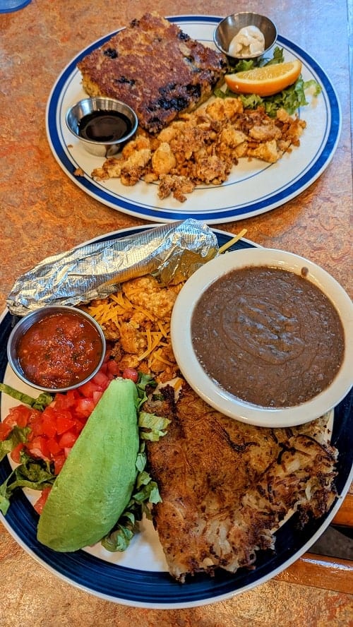 vegan tex mex scramble in front of a blueberry cornbread cake on a wood table at boudin creek in austin