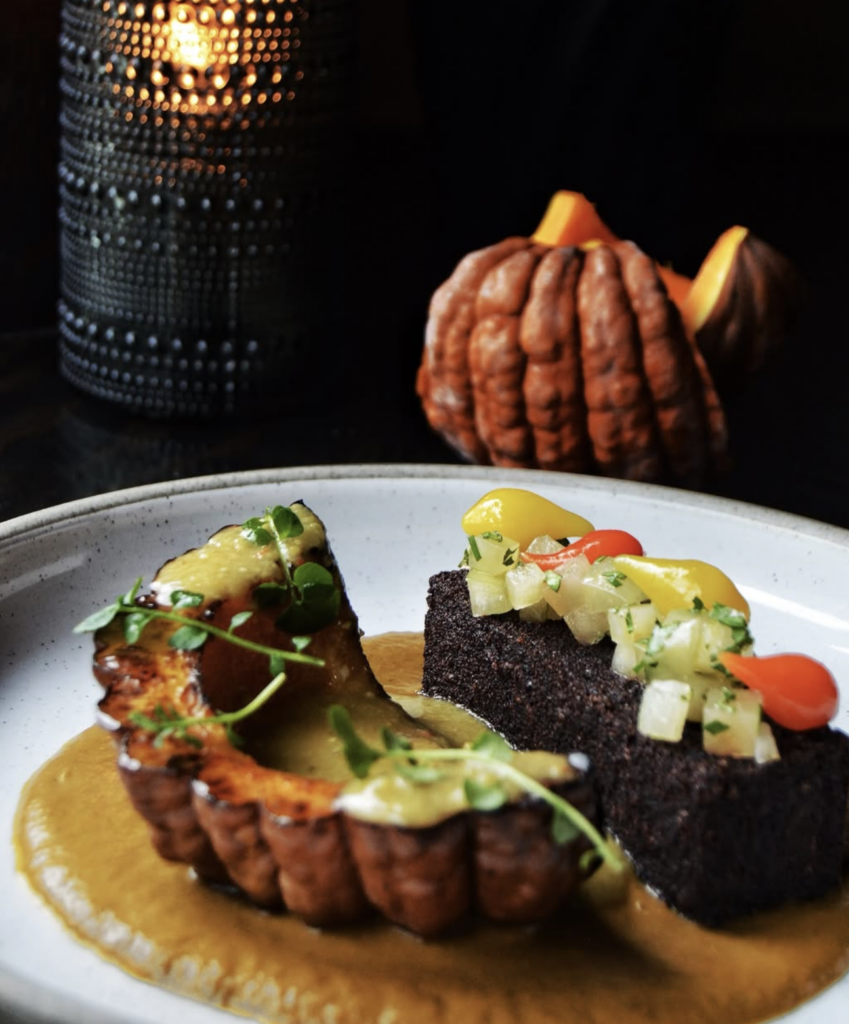 Creative vegan fine dining dish at The Acorn Vancouver featuring roasted squash, savory cake, and seasonal garnishes.