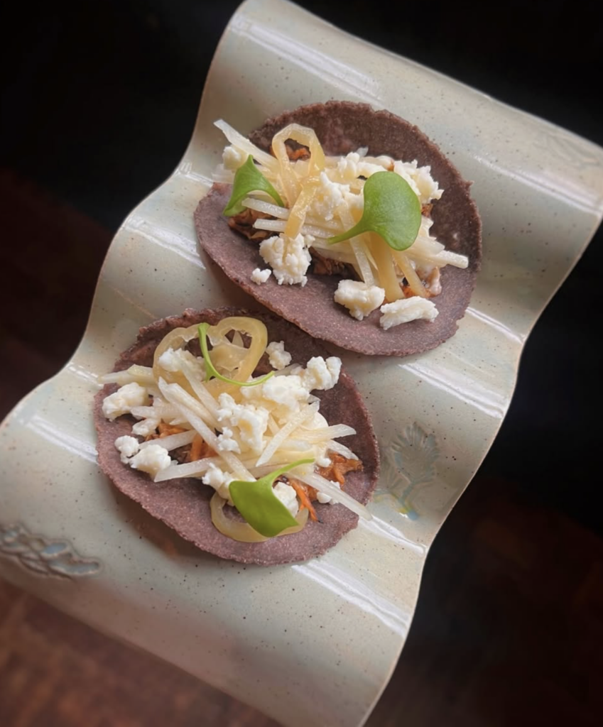 Plated vegan tacos at The Acorn Vancouver with house-made tortillas, pickled vegetables, and plant-based cheese.