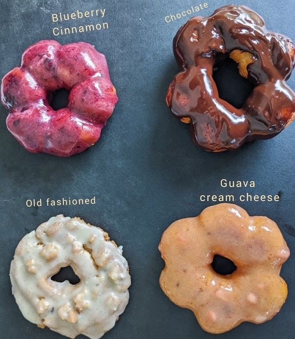 four vegan and gluten free donuts on a dark background topped with a variety of colorful glazes at betty bot shop in chicago