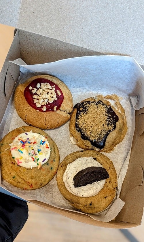 a box of four vegan stuffed cookies topped with cream, cookies, jam and sprinkles from bonus bakery in vancouver