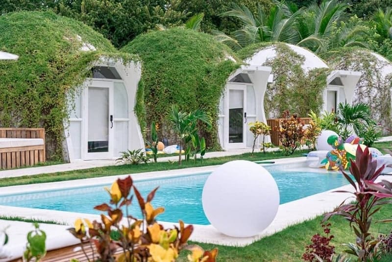 the white igloo shaped guest rooms in front of a pool at the vegan friendly igloo beach lodge resort in costa rica