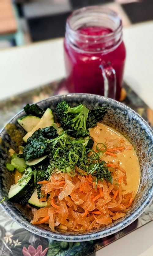 vegan coconut curry bowl next to a beet juice at le botaniste vegan restaurant in nyc