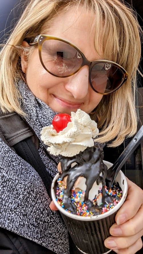 rebecca gade sawicki with a vegan ice cream sundae in a cup topped with chocolate drizzle sprinkles, whipped cream, and a cherry from perverted in vancouver