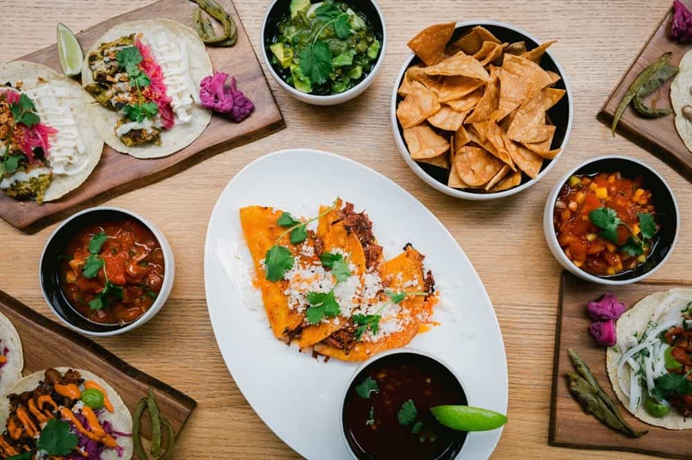 vegan tacos, corn chips, and salsas spread across a wood table at sentir in nyc