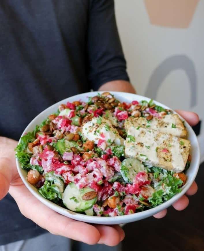 a vegan salad topped with a creamy dressing and chick'n held with two hands at sorry ive got plants in toronto