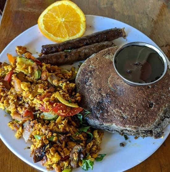 vegan pancakes, tofu scramble, and sausage links on a white plate at the naam in vancouver