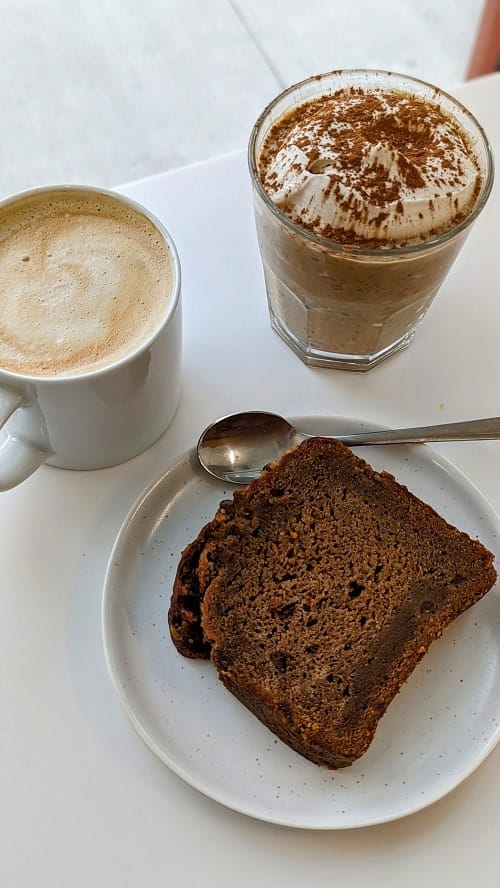 vegan banana bread, overnight oats and a coffee sitting on a white table at to live for bakery in vancouver