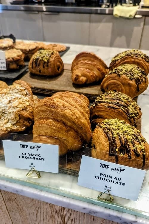 golden vegan croissants and pastries in a dessert case at turf in vancouver