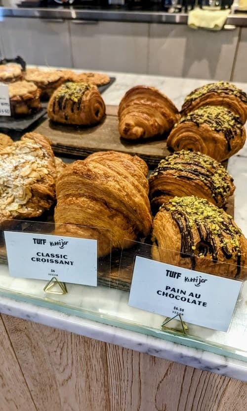 golden vegan croissants and pastries in a dessert case at turf in vancouver