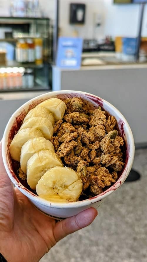 vegan acai bowl topped with granola and sliced banana at the glory in vancouver