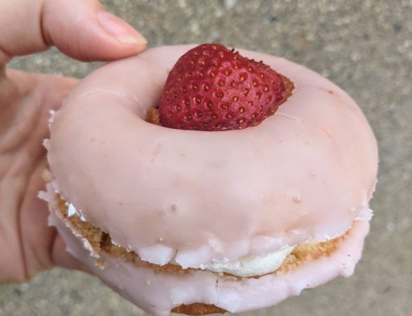vegan donut topped with a pink strawberry glaze and a sliced strawberry and filled with cream from liberation donuts in chicago