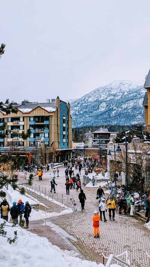 snowy whistler village with a small crowd of people walking during the winter