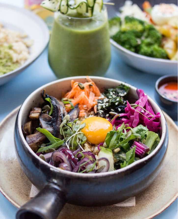 vegan bibimbap bowl with colorful veggies on a full table at O Gambuzino in lisbon