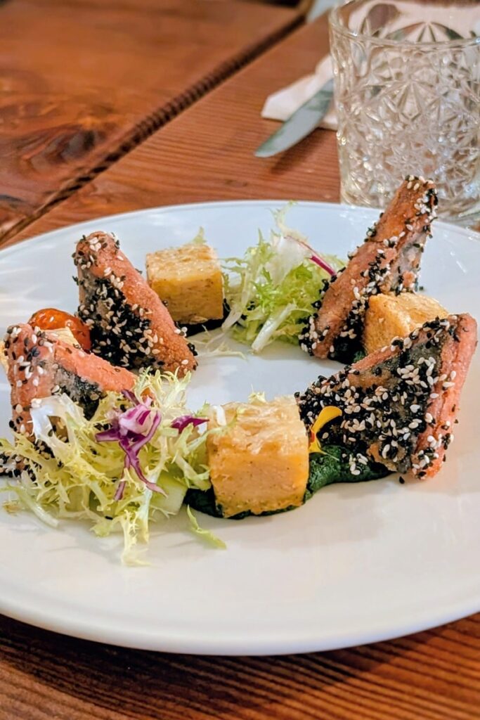 triangles of vegan salmon on a white plate with greenery from kong in lisbon