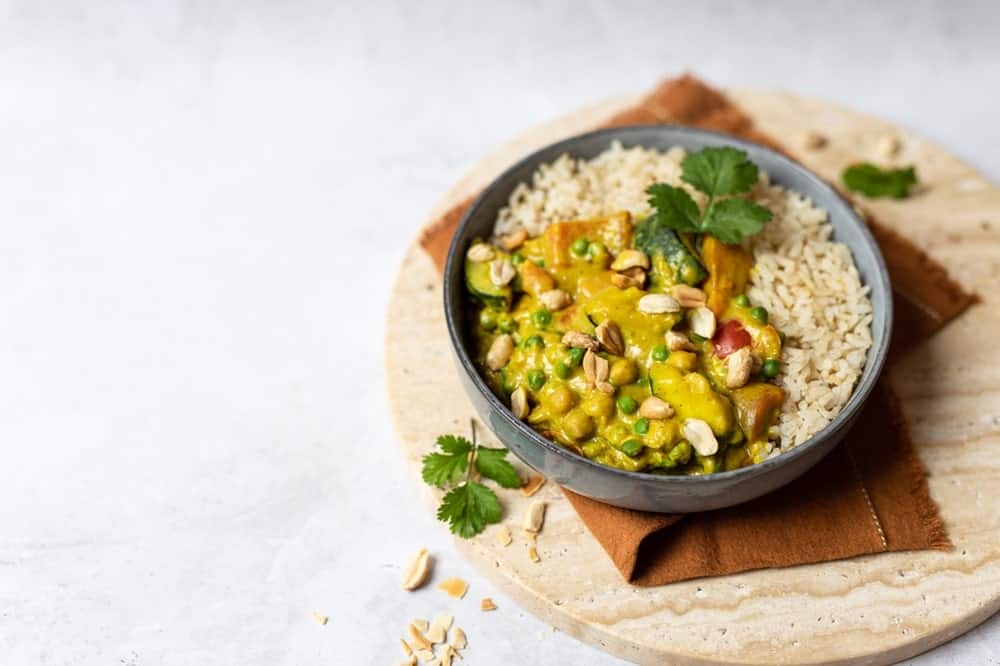 a round black bowl filled with a green vegan curry and brown rice from the vegan restaurant soa in Paris